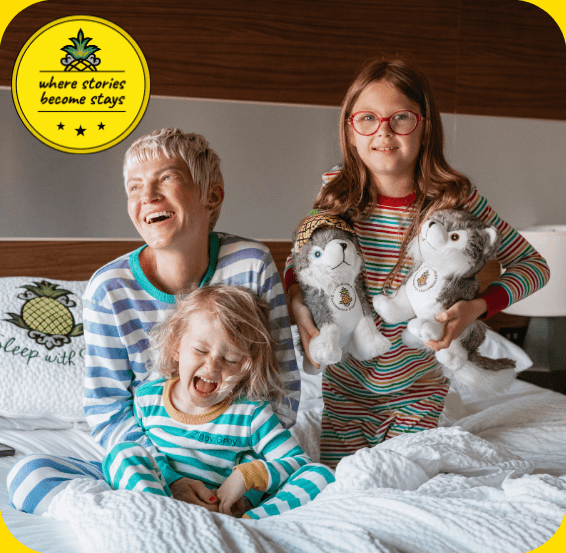 Family in matching pajamas laughing on a Staypineapple hotel bed